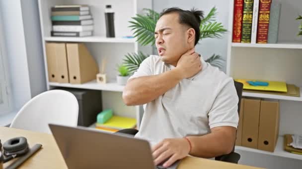 紧张的年轻中国商人与颈痛作斗争 紧紧抓住办公室的笔记本电脑 — 图库视频影像