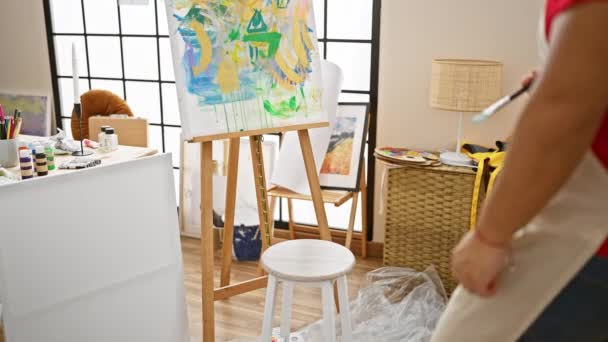 彼のアートスタジオに拘束された若い中国人男性アーティストは 考えるのをやめ 絵画やペイントブラシに吸収され 椅子に座って — ストック動画