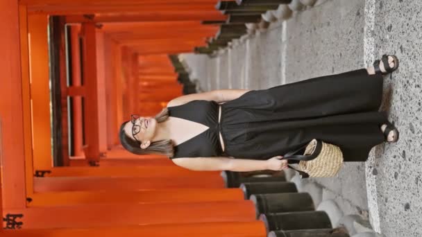 信心十足地戴着眼镜 咧嘴笑着 怀着敬畏的心情环顾四周 凝视着位于京都神殿的橙红色的环形山隧道 — 图库视频影像