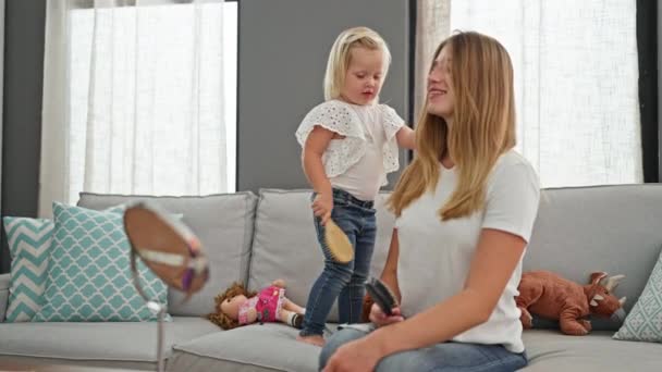 自信を持った慎重な母親は快適に座り ソファーに娘の髪を慰めます 家で温かい家族のシーン — ストック動画