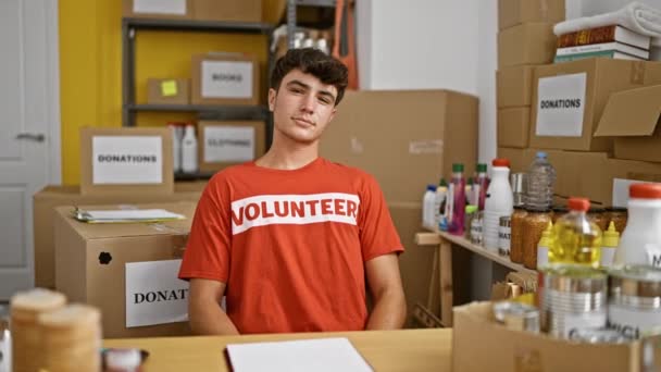 Joven Adolescente Hispano Señalando Uniforme Voluntario Sonriendo Centro Caridad — Vídeos de Stock