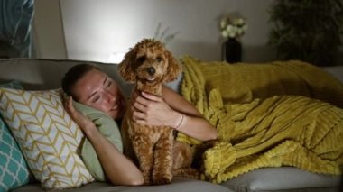 Köpekli beyaz bir kadın evdeki kanepede yatıyor.