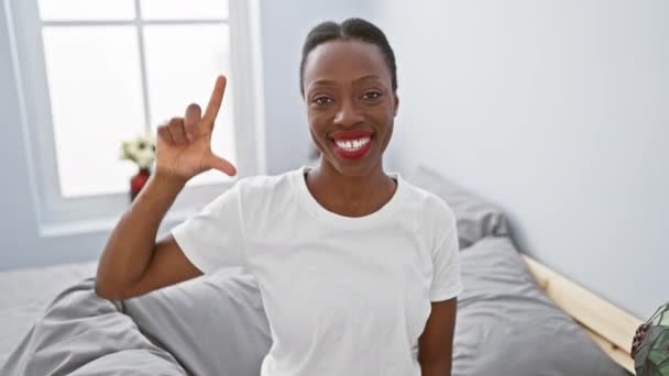 Χαρούμενη Αφροαμερικάνα Ξαπλωμένη Στο Κρεβάτι Στο Καλαίσθητο Υπνοδωμάτιο Ευτυχισμένη Δείχνει — Αρχείο Βίντεο