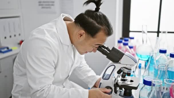 Allvarlig Ung Kinesisk Man Professionell Vetenskapsman Koncentrerar Sig Ett Mikroskop — Stockvideo