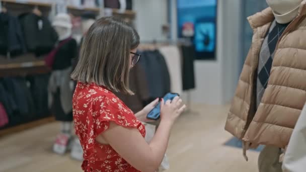 迷人的拉蒂娜戴眼镜的女人沉迷于零售治疗 在一家精品店抢购时尚商品 她在电话里寻找最好的交易 — 图库视频影像