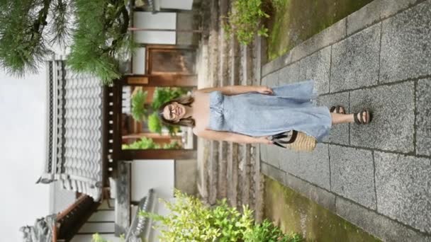 惊慌的戴眼镜的女人自信地向摄像机走去 她灿烂的笑容点亮了背景中历史性的敬神寺 在日本旅途愉快 — 图库视频影像