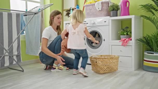 コーカサス人の母親と娘は 洗濯室の洗濯機のおもちゃ 家族の家事の写真に真剣に集中しています — ストック動画
