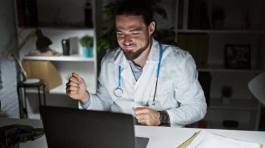 Genç İspanyol doktor klinikte dizüstü bilgisayar dansı yapıyor.