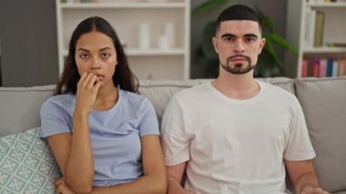 Güzel bir çift evde birlikte eğleniyor ve rahatlıyor. Koltukta güven içinde oturuyorlar. Elleri kafalarında, güneş ışığıyla dolu oturma odasında gülümsüyorlar..