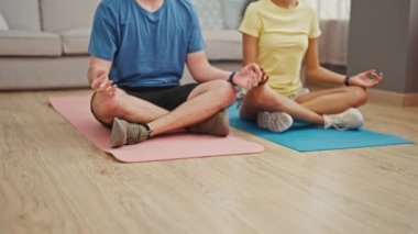 Güzel bir çift, birbirine sırılsıklam aşık, atletik vücutlarını esnetiyorlar ve yoga eğitimiyle sağlıklı bir yaşam tarzını kucaklıyorlar, rahat evlerinin zemininde birlikte oturuyorlar..