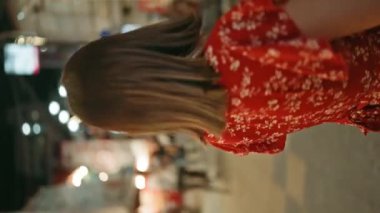 Gözlüklü, kendine güvenen ve güzel İspanyol bir kadın, durduğu yerde neşe ve başarının portresi, gülümseyen ve etrafa bakan, Japon şehir hayatının tadını çıkaran.