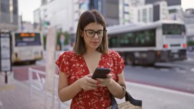 Tokyo 'nun hareketli sokaklarında, gözlüklü, teknoloji meraklısı bir gezgin güzel bir İspanyol kız telefon uygulamasını endişeyle taksisini bekliyor..