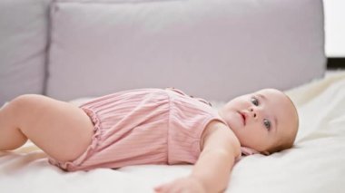 Yeni doğmuş sevimli bir kız bebek, beyaz, rahat bir kanepeye uzanmış, evinde battaniyeye sarılmış, masum bebek yaşam tarzının özünü içeride yakalıyor.