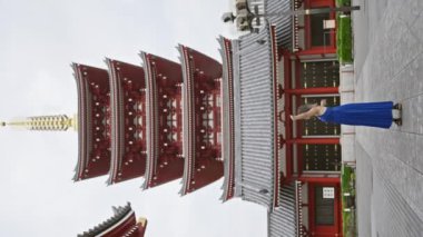 Gözlüklü neşeli İspanyol kadın, kolları açık, Senso-ji tapınağına bakıyor, güzel bir gülümsemeyle Tokyo tasasız yaşam tarzını kucaklıyor..