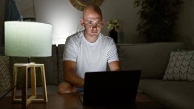 Genç İspanyol adam dizüstü bilgisayar kullanıyor. Kanepede oturmuş kutlama yapıyor.