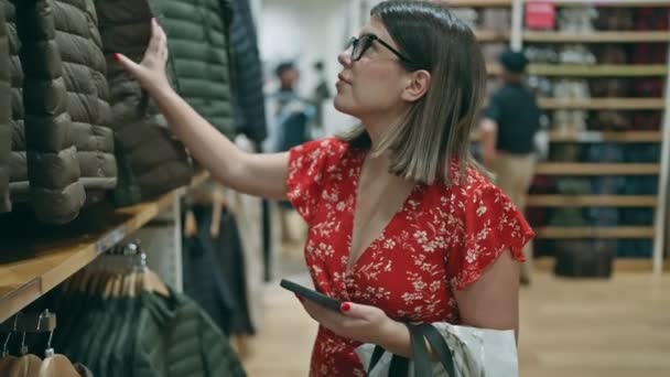 迷人的拉蒂娜戴眼镜的女人沉迷于零售治疗 在一家精品店抢购时尚商品 她在电话里寻找最好的交易 — 图库视频影像