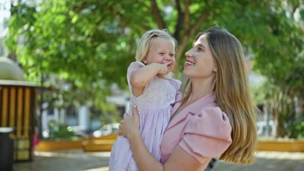 自信に満ちた母親 娘の周りに包まれた腕 日光浴公園にいる笑顔 ポジティブさと幸せを放射する — ストック動画