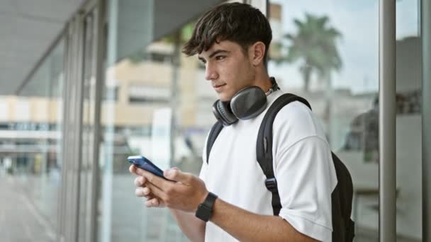 Jovem Adolescente Hispânico Usando Fones Ouvido Mochila Usando Smartphone Universidade — Vídeo de Stock