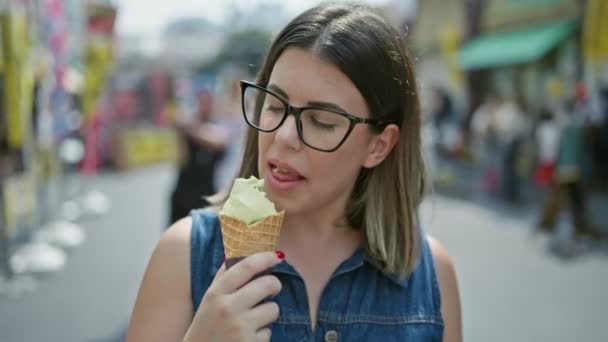 陽気で美しいヒスパニック系女性のメガネは 賑やかな月明けの外市場の中で美味しいアイスクリームコーンを幸せに貯めています 東京夏の楽しみ — ストック動画