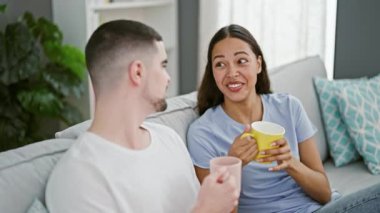 Güzel bir çift kanepede birlikte oturup evde kahve içiyor.