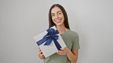 Mutlu, genç, İspanyol bir kadın dişlek bir gülümseme sergilerken, beyaz izole edilmiş bir arka plana karşı elinde bir doğum günü hediyesi paketi tutuyordu.