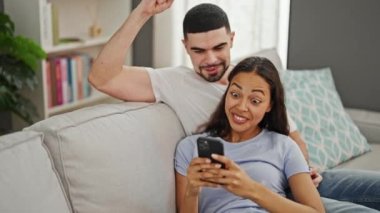 Kanepede birlikte oturan güzel bir çift, akıllı telefonlarıyla kendilerine güvenen, evlerinin içinde sıcak bir beşlik paylaşan.
