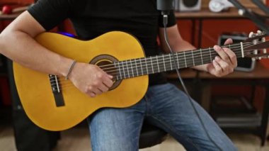 Young hispanic man musician singing song playing classical guitar at music studio
