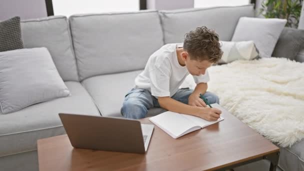 ラップトップの助けを借りて紙にペンを置き 自分のアイデアをノートブックに書き 快適に家のリビングルームに貼り付けた 愛らしいブロンドの少年 — ストック動画