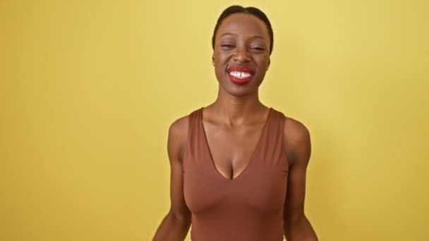 兴高采烈的非洲裔美国妇女站在那里 带着愉快的微笑和胜利的表情庆祝胜利 在孤立的黄色背景下举起双手欢呼 — 图库视频影像