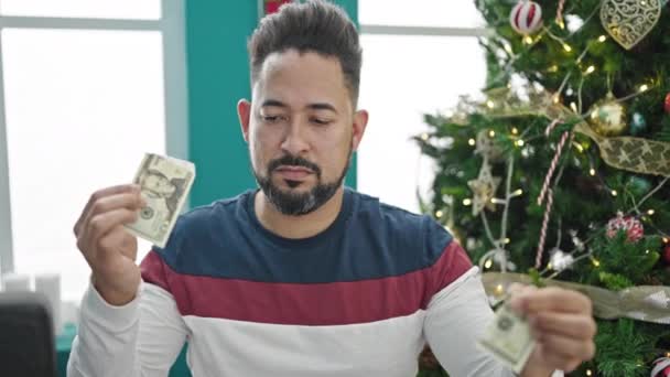 若いラテン語の男 自宅でクリスマスを祝う20ドルの紙幣を破る — ストック動画
