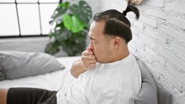 坐在床上咳嗽的中国年轻人在卧室里 — 图库视频影像