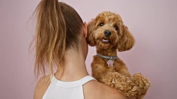 年轻的高加索女人 带着狗向后抱在孤立的粉色背景之上 — 图库视频影像
