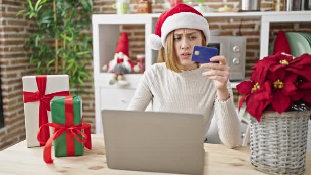 年轻的金发女人带着笔记本电脑和信用卡购物 庆祝圣诞节 她在饭厅里看起来很不高兴 — 图库视频影像