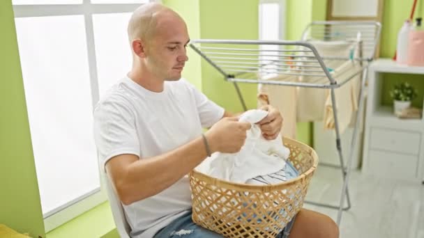 在洗衣房 他的恐慌年轻人拿着篮子坐在椅子上 衣服闻起来像毛巾 — 图库视频影像