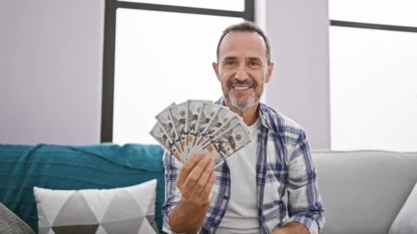 Hombre Mediana Edad Con Pelo Gris Contando Dólares Sentado Sofá — Vídeo de stock