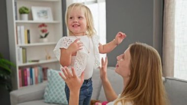 Kafkasyalı anne ve kız, kanepede zıplarken kıkırdayarak birbirlerine bağlanıyorlar, rahatlatıcı evlerinde neşe saçıyorlar.