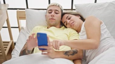 Yatak odasında akıllı telefon kullanan güzel bir çift.  