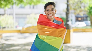 Parkta gökkuşağı bayrağı takan kendine güvenen güzel İspanyol kadın.