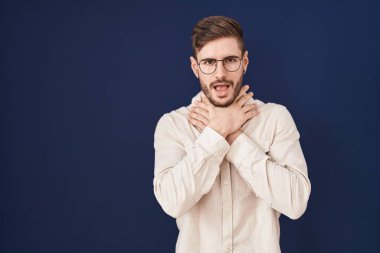 Mavi arka planda sakallı İspanyol bir adam bağırıyor ve boğuluyor çünkü acı verici bir boğulma. Sağlık problemi. Boğulma ve intihar konsepti. 