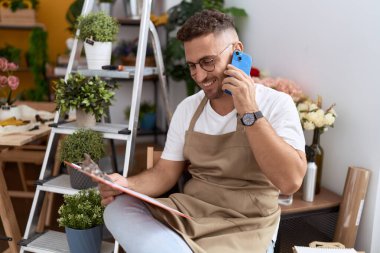 Çiçekçide akıllı telefondan konuşan genç İspanyol çiçekçi.