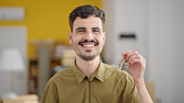 Yeni evin anahtarını elinde tutarak gülümseyen İspanyol genç adam.