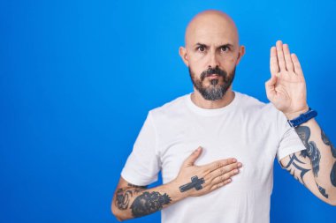 Mavi arka planda duran, elleri göğsünde ve avuçları açık küfür eden, sadakat yemini eden İspanyol bir adam. 