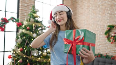 Genç ve güzel İspanyol kadın evde Noel 'i kutlamak için müzik dinliyor.