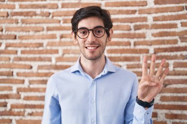 Duvarın arkasında duran İspanyol genç adam dört numarayı gösterip işaret ederken kendinden emin ve mutlu bir şekilde gülümsüyor.. 