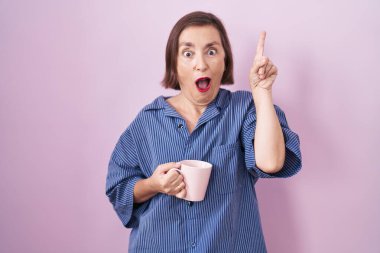 Orta yaşlı İspanyol kadın kahve içiyor ve başarılı bir fikirle işaret ediyor. Heyecanlı ve mutlu. Bir numara.. 