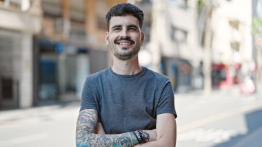 Genç İspanyol adam gülümsüyor. Kendine güveni tam. Sokakta çapraz hareketlerle duruyor.