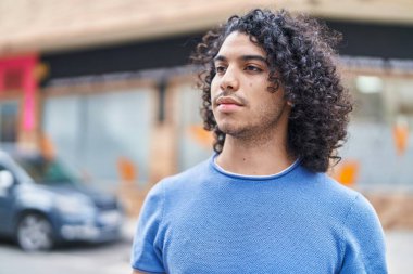 Young latin man looking to the side with serious expression at street