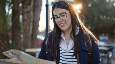 Sırt çantalı genç İspanyol kadın turist sokak haritasına bakıyor.