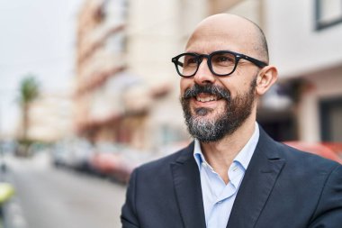 Genç kel iş adamı gülümsüyor. Kendine güveni tam caddede duruyor.