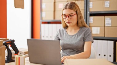 Young blonde woman ecommerce business worker using laptop at office